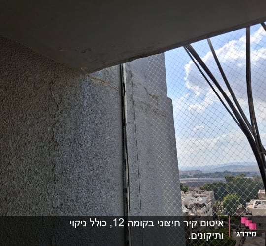 תמונה של קיר עם רשת בטיחות ונוף עירוני ברקע